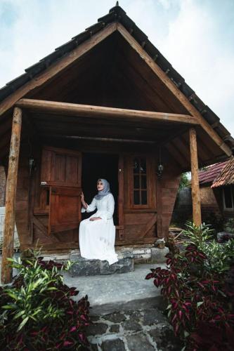 a woman sitting in the doorway of a small house at Singgasana Villa & Resto in Bedakah