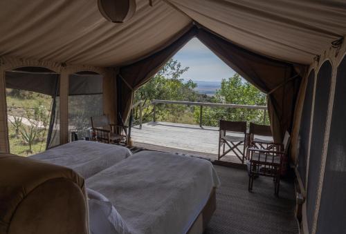a tent with two beds and a view of a porch at Mara Elatia Camp in Masai Mara