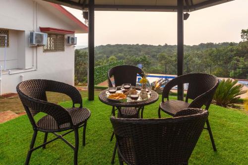 four chairs and a table with food on a patio at Emerald Greens by VEO - Part of StayVista in Lonavala
