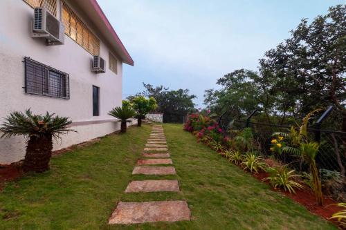 a garden path next to a building at Emerald Greens by VEO - Part of StayVista in Lonavala