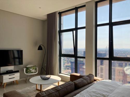 a living room with a couch and large windows at Urban Awe Apartment: iTowers 21st Floor in Gaborone