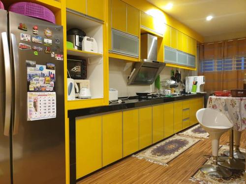 cocina con armarios amarillos y nevera en Mountain View Homestay, en Seremban