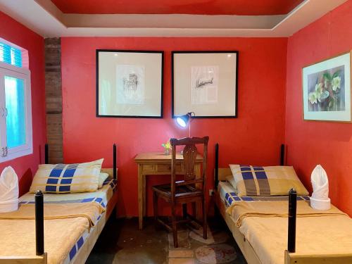 two beds in a room with a desk and a red wall at Casa San Pablo B & B in San Pablo
