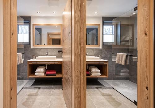a bathroom with two sinks and two mirrors at Apartment NH96 inklusive kostenfreiem Eintritt in die Alpentherme in Bad Hofgastein