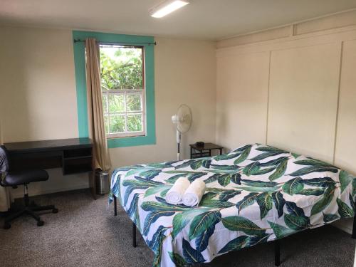 a bedroom with a bed and a desk and a window at Pahoa Village Hostel in Pahoa