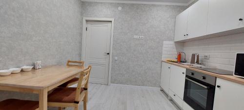 a kitchen with a wooden table and a dining room at Аэропорт 10 минут жк Будапешт163 in Astana
