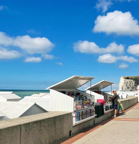 un homme debout à côté d'un kiosque à livres sur la plage dans l'établissement La Découverte, appartement front de mer Mers, à Mers-les-Bains