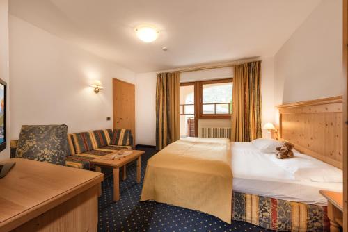 a hotel room with a bed and a chair at Family Hotel Adriana in Ledro