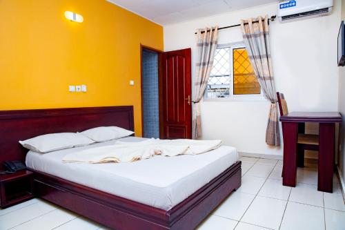 - une chambre avec un lit et un mur jaune dans l'établissement krEMLin, à Douala