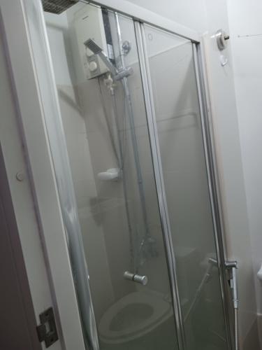 a shower stall with a glass shower door at 1 BR with poolside view balcony in Manila