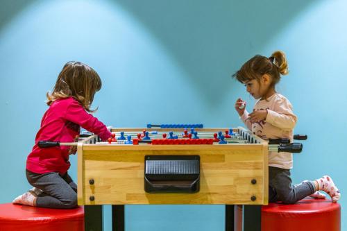 two little girls playing with a table with toys at Family Hotel Adriana in Ledro