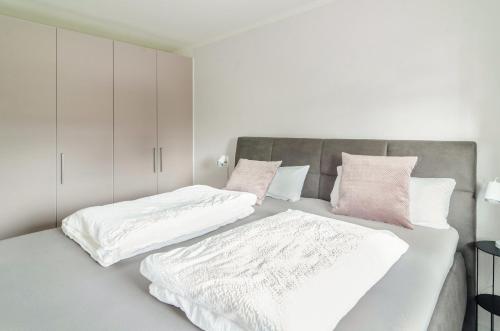 1 Schlafzimmer mit 2 Betten mit weißen und rosa Kissen in der Unterkunft Ferienwohnung Lux in Überlingen