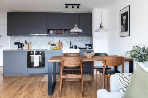 cocina con armarios azules, mesa y sillas en La Ruinette - Modern 1 Bed, 3 Mins From Cable Car, en Verbier