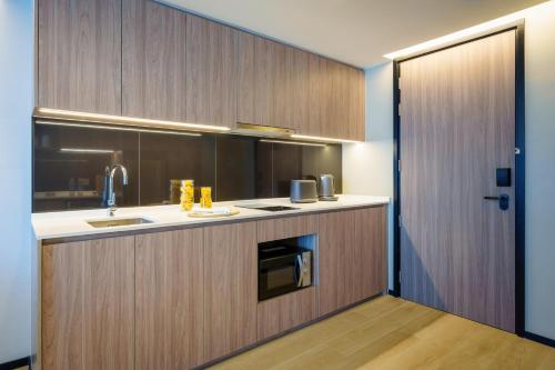 a kitchen with wooden cabinets and a sink at Somerset Pattaya in Pattaya Central