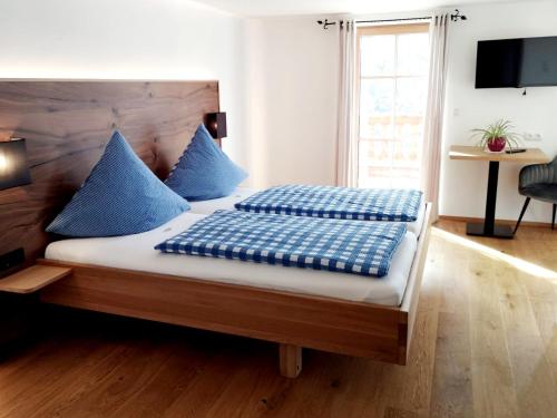 a bedroom with a bed with blue pillows on it at Berggasthof Bichlersee in Oberaudorf