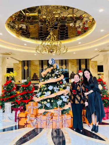 two women standing in front of a christmas tree at Sandals Vista Hotel in Bao Loc