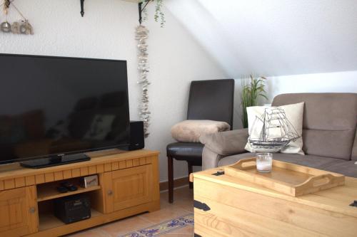 un soggiorno con TV a schermo piatto su un centro di intrattenimento in legno di Ferienwohnung Landgang 25494 a Weener