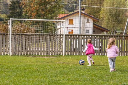 two little girls playing with a soccer ball in the grass at Family Hotel Adriana in Ledro