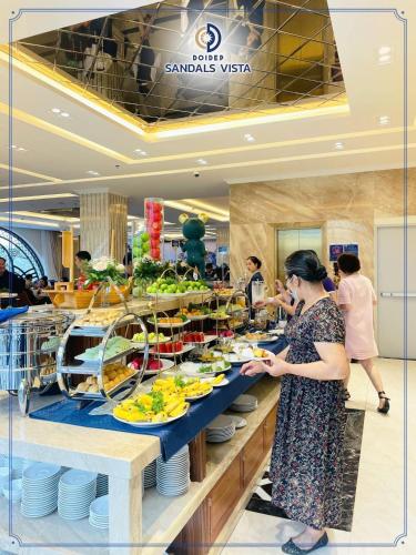 a woman standing in front of a buffet line with food at Sandals Vista Hotel in Bao Loc