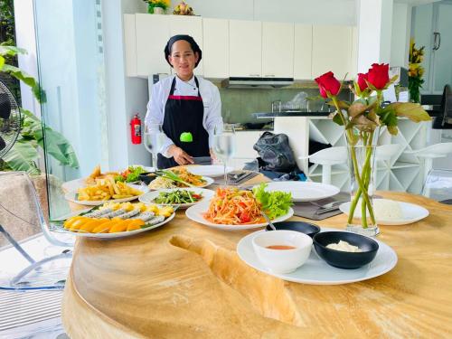 a woman standing in front of a table with plates of food at Sunshine Ocean Sea View in Chaweng