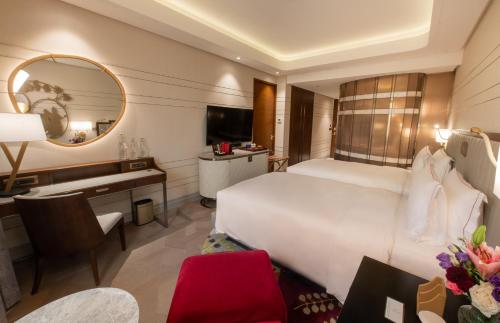 a hotel room with a large white bed and a desk at Admiral Hotel Manila - MGallery Collection in Manila