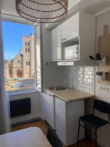 une cuisine avec évier et une fenêtre avec un bâtiment dans l'établissement Studio nature centre ville Gannat, à Gannat
