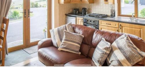 un sofá de cuero marrón con almohadas en la cocina en ocean view cleggan en Cleggan