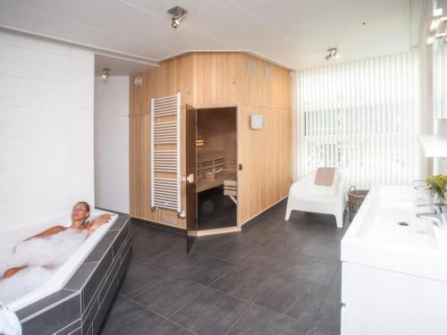 a man laying in a bath tub in a bathroom at Luxe vakantiehuis in Friesland in Joure