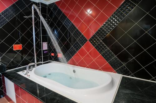 a bath tub in a bathroom with red and black tiles at Summer House Motel in Tainan