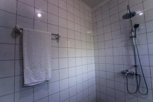 a white tiled bathroom with a towel hanging on a shower at Melvis' place in Dar es Salaam
