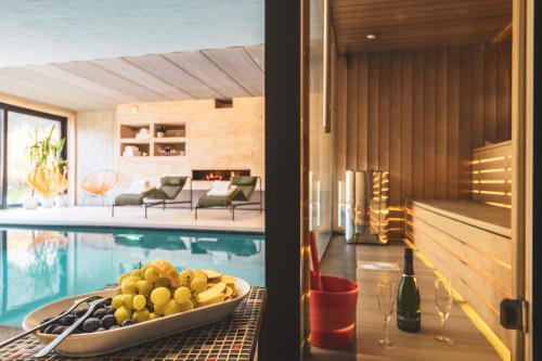 a dining table with a bowl of fruit next to a swimming pool at Daft Boutique Hotel & Glamping in Malmedy