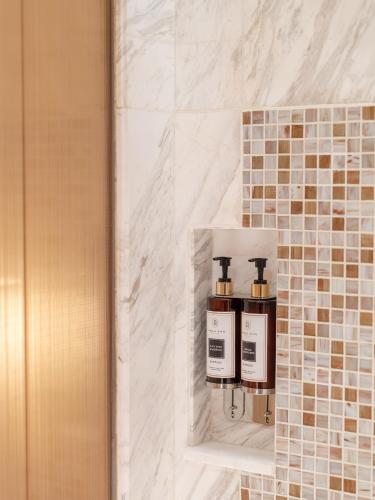 a bathroom with two soap dispensers on a tiled wall at Admiral Hotel Manila - MGallery Collection in Manila