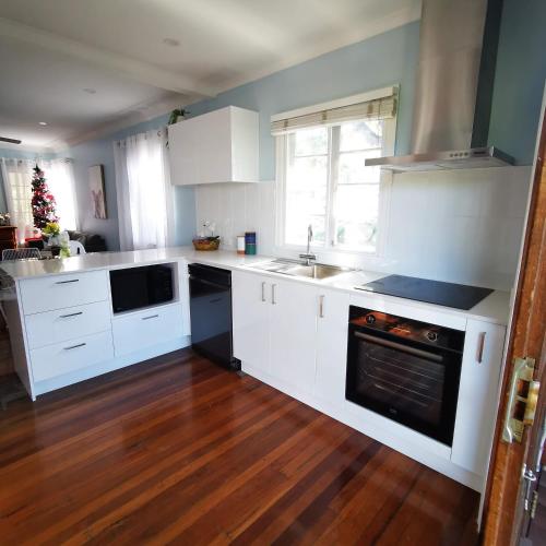 a kitchen with white appliances and a wooden floor at OXLEY Mineral Pool & Private Home suburbanSTAY in Brisbane