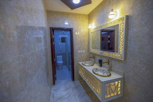 a bathroom with two sinks and a mirror and a toilet at Villa Mans 2 in Al-ʿUla