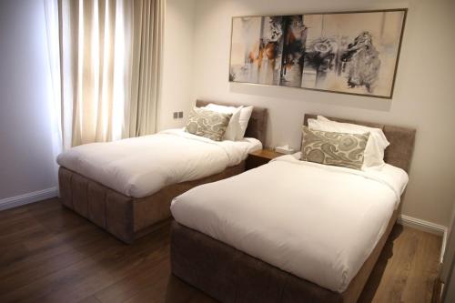 two beds in a hotel room with white sheets at Vittori Palace Hotel and Residences in Riyadh