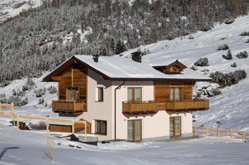 a house in the snow with snow covered mountains at BAITA NOEMI in Livigno