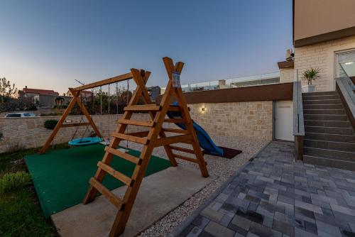 a wooden ladder in a yard with a playground at Villa Azeret ZadarVillas in Maslenica