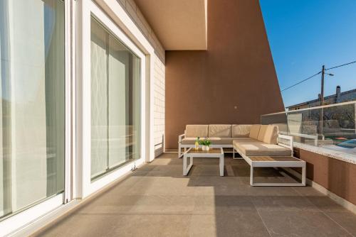 a patio with a couch and a table on a balcony at Villa Azeret ZadarVillas in Maslenica