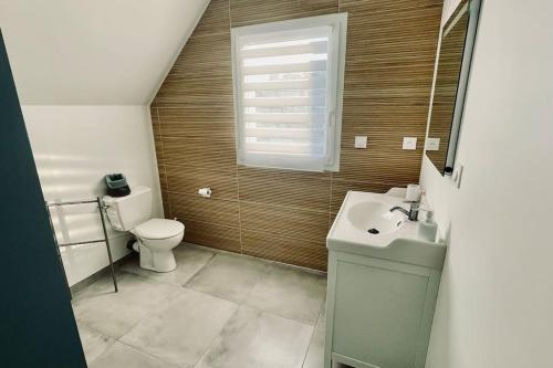La salle de bains est pourvue de toilettes, d'un lavabo et d'une fenêtre. dans l'établissement Maison à l'orée du bois du Kador, à Crozon