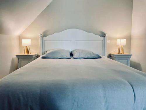 1 cama blanca grande con 2 lámparas en 2 mesas en Maison à l'orée du bois du Kador, en Crozon