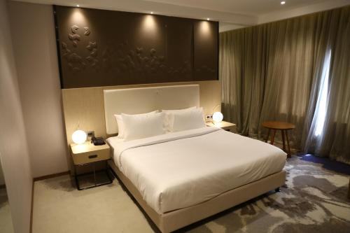 a bedroom with a large white bed and two tables at Clarks Inn Suites Raipur in Raipur