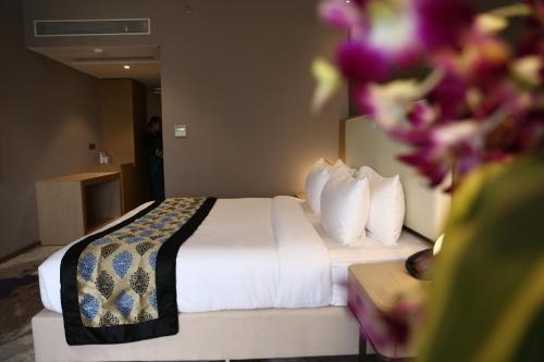 a hotel room with a bed with white sheets and pillows at Clarks Inn Suites Raipur in Raipur