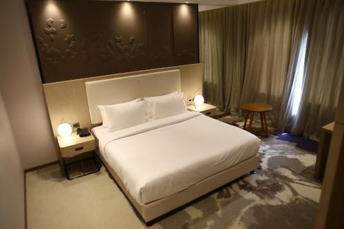 a bedroom with a large white bed and two lamps at Clarks Inn Suites Raipur in Raipur