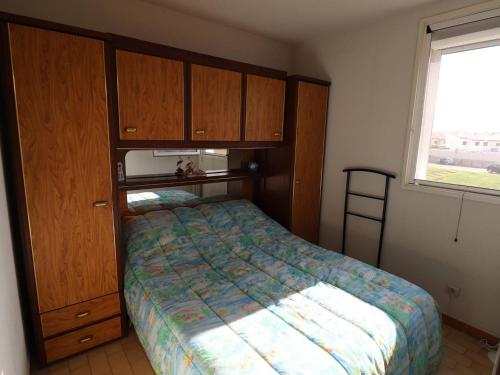 - une chambre avec un lit, des armoires en bois et une fenêtre dans l'établissement 2 pièces près de la mer au Grau-du-Roi, climatisation, parking - FR-1-307-182, au Grau-du-Roi