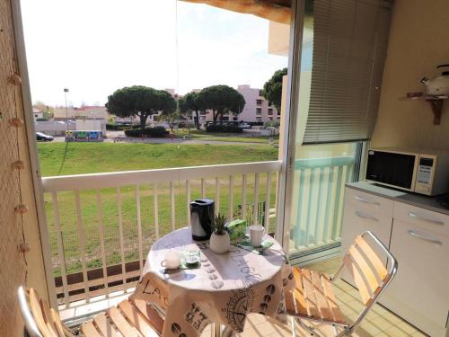 un balcon avec une table et des chaises et une cuisine dans l'établissement 2 pièces près de la mer au Grau-du-Roi, climatisation, parking - FR-1-307-182, au Grau-du-Roi