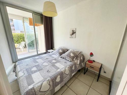une chambre avec un lit et une grande fenêtre dans l'établissement Charmant T2 avec belle terrasse expo Sud, parking privé, proche plage et commerces - FR-1-307-187, au Grau-du-Roi