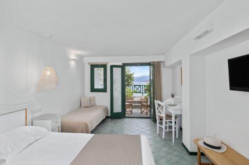 a hotel room with a bed and a table and chairs at Erofili Beach Hotel in Armenistis