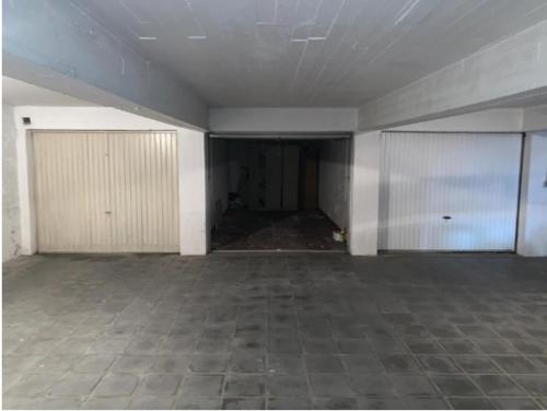an empty room with two garage doors and a tile floor at Knokke Modern Studio in Knokke-Heist