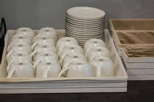 a tray filled with white mugs and stacks of plates at Inga Hotel Yerevan in Yerevan
