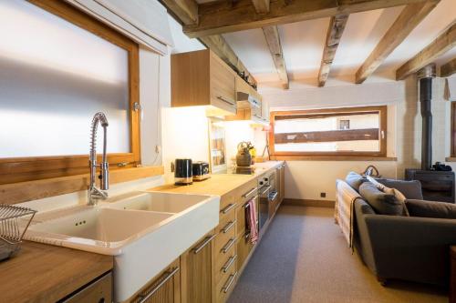 uma cozinha com um lavatório e um sofá em Charming Old Barn Converted Into A Cosy And Stylish Home em Le Châble